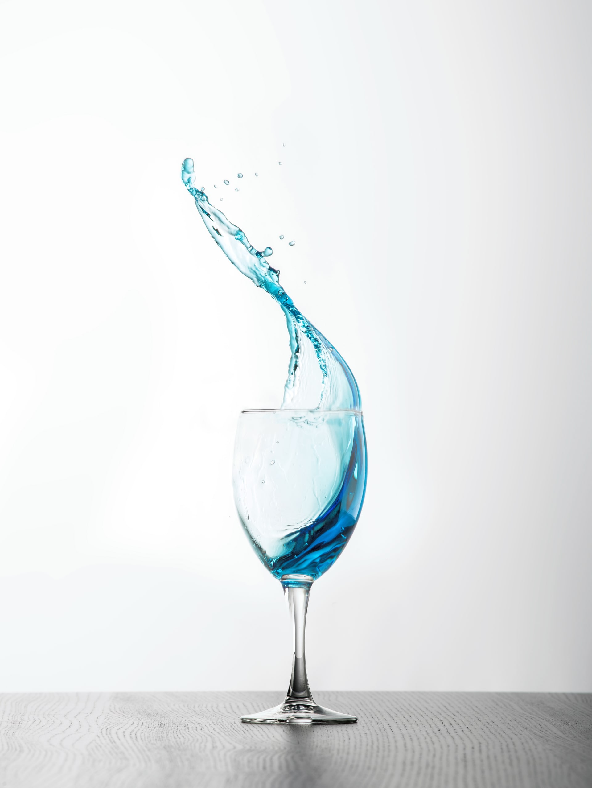 Blue water suspended in motion above a glass, photographed by Mark Richardson