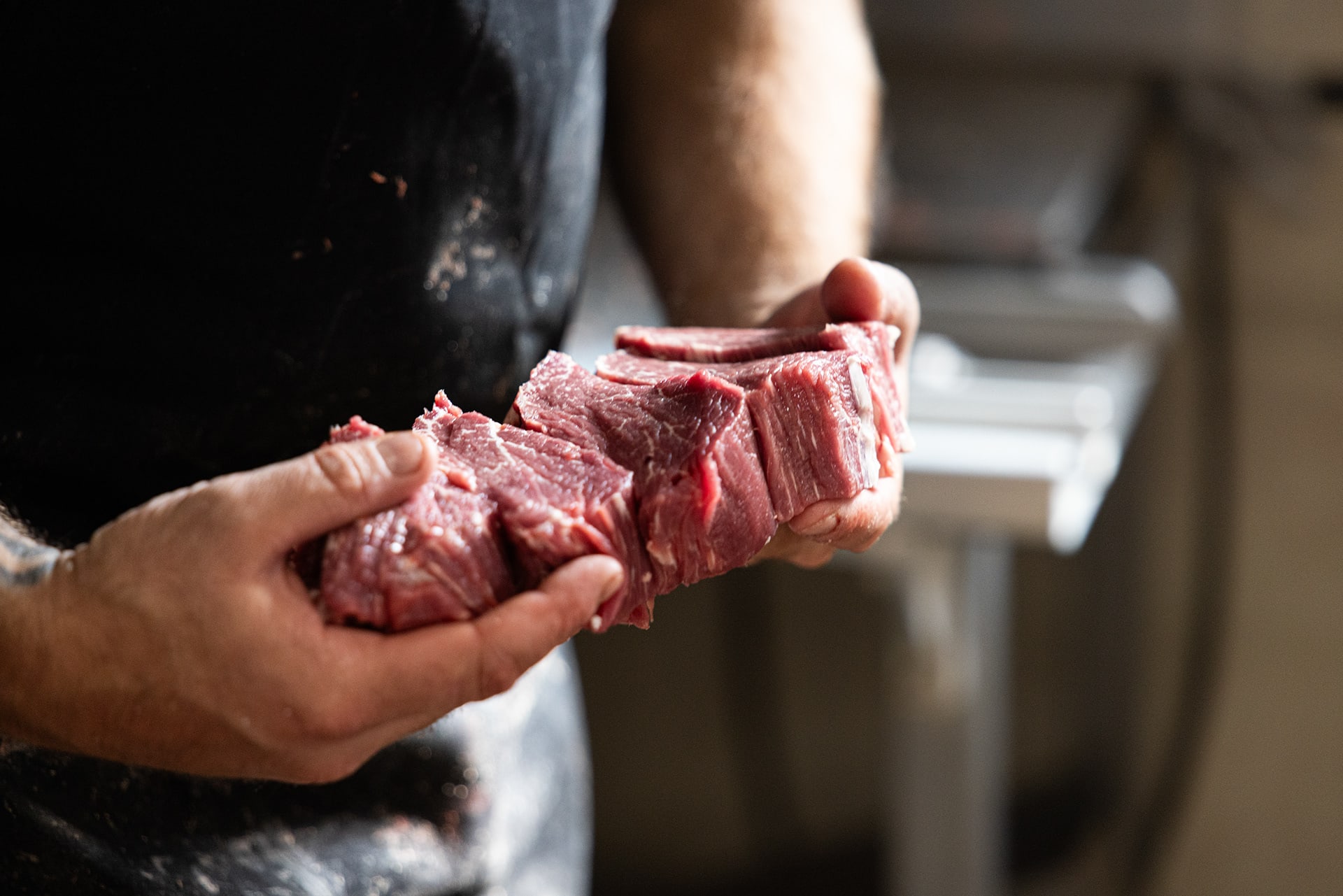 A butcher presenting a cut of meat in the shop